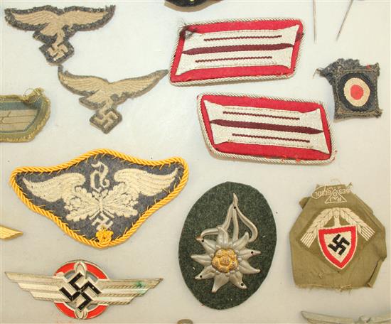 A collection of various German Third Reich cap badges, cloth badges and pins